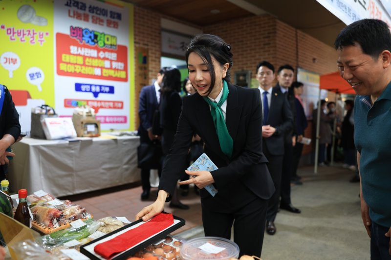 김건희 여사가 14일 대전 중구 태평전통시장을 방문, 백원경매 행사장에서 윤석열 대통령이 직접 맸던 넥타이를 기부하고 있다. 경매는 백원으로 시작하며 발생한 수익금으로 육아꾸러미를 제작해 태평동에 출생신고한 신생아들에게 기부된다. [대통령실 제공] 연합뉴스