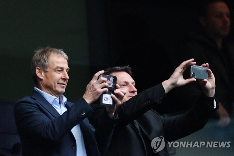 토트넘 홋스퍼 경기장 찾은 클린스만 감독 Former German football player Jurgen Klinsmann (L) takes pictures with his mobile phone during the English Premier League football match between Tottenham Hotspur and Bournemouth at Tottenham Hotspur Stadium in London, on April 15, 2023. (Photo by Adrian DENNIS / AFP) / RESTRI