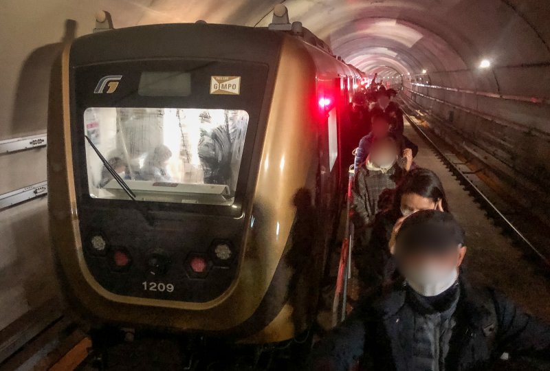 21일 오후 6시 30분께 김포 골드라인 경전철이 김포공항역에서 고촌역사이에서 멈춰서 시민들이 큰 불편을 겪고 있다. 이 차량에 50여분간 갇혀 있던 약 300여명의 승객들이 열차 선로 위 비상통로로 고촌역까지 걸어가고 있다. 2020.12.21/뉴스1 ⓒ News1 김명섭 기자
