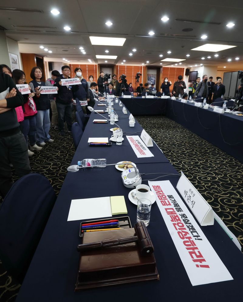 18일 서울 중구 한국프레스센터에서 열린 최저임금위원회 제1차 전원회의에 앞서 한국노총, 민주노총 관계자들이 권순원 공익위원의 사퇴를 촉구하는 손팻말을 들고 있다. 박준식 최저임금위원장은 참석하지 않아 자리가 비어있다.