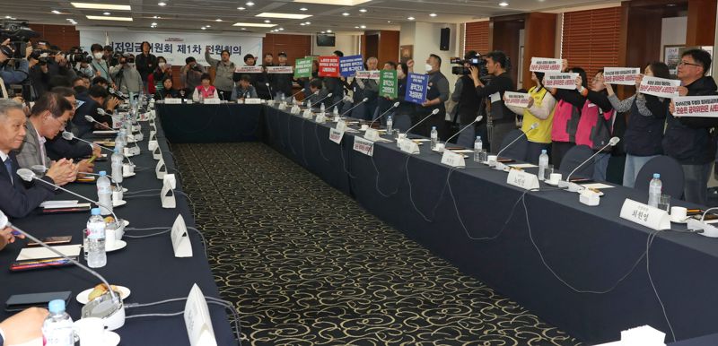 18일 서울 중구 한국프레스센터에서 열린 최저임금위원회 제1차 전원회의에 앞서 한국노총, 민주노총 관계자들이 권순원 공익위원의 사퇴를 촉구하는 손팻말을 들고 있다.