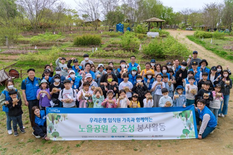 우리은행은 지난 23일 마포구 상암동 소재 노을공원에서 숲 조성 봉사활동을 실시했다. 참여한 임직원 및 가족들이 묘목을 들고 기념촬영을 하고 있다. 우리은행제공