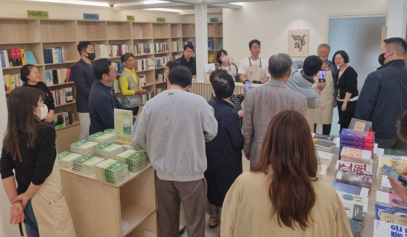 29일 양산 평산책방에 손님들이 가득 찬 가운데 문재인 전 대통령이 한 시민과 기념사진 촬영을 하고 있다./뉴스1 이현동 기자