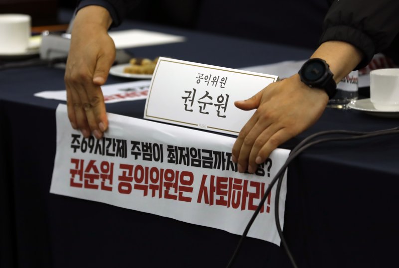 지난달 18일 파행된 최저임금위원회 제1차 전원회의 당시 모습. 양대노총 관계자들이 권순원 공익위원 자리에 피켓을 붙이고 있다. 뉴시스