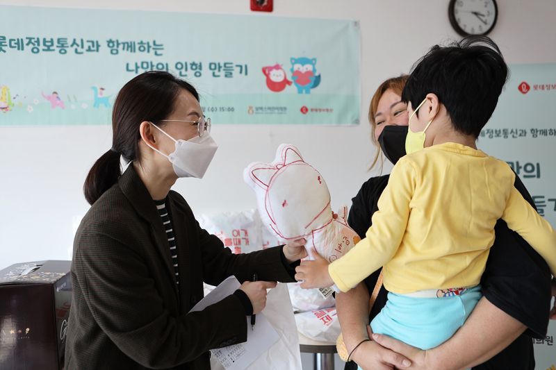 롯데정보통신 직원들이 보바스어린이의원에서 입원중인 환아에게 직접 그린 그림으로 만든 인형을 전달하고 있다. 롯데정보통신 제공