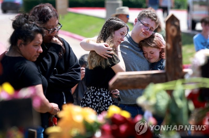ALLEN, TEXAS - MAY 08: (L-R) Jenni Seeley, Dakota Britvich, and Abbi Boyd hug as they visit a memorial set up near the scene of a mass shooting at the Allen Premium Outlets mall on May 8, 2023 in Allen, Texas. Eight people were killed and seven wounded in the Saturday attack in which the gunman was 