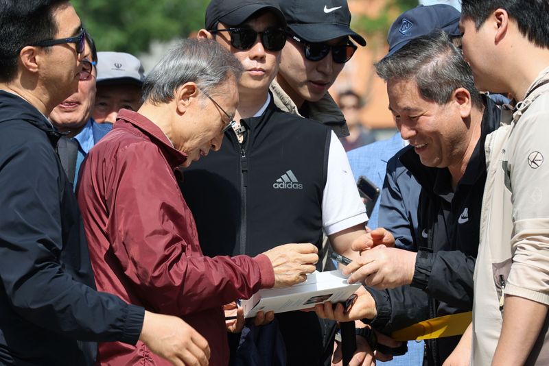 이명박 전 대통령이 15일 서울 청계천에서 옛 참모들과 함께 산책하기에 앞서 청계광장에서 지지자들에게 자필 서명을 해주고 있다. 사진=서동일 기자