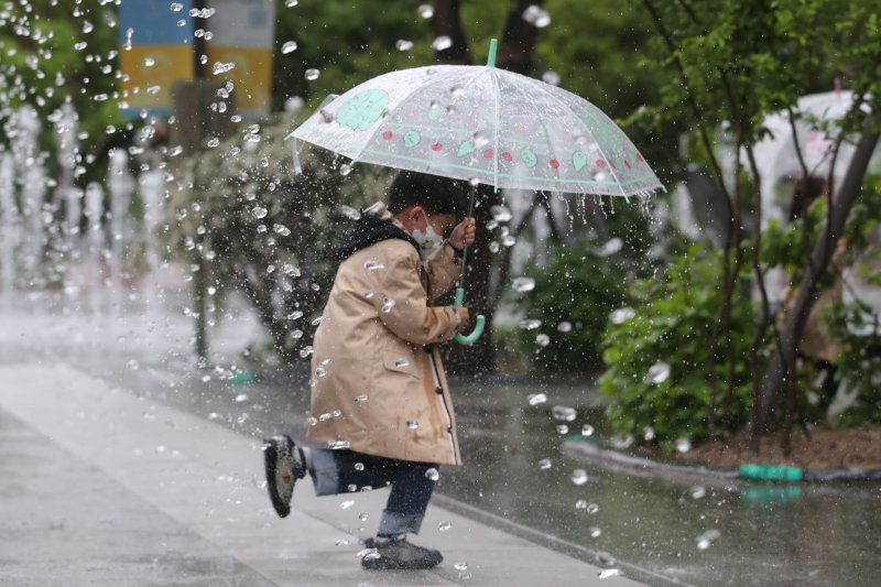 [서울=뉴시스] 권창회 기자 = 지난 5일 오전 서울 종로구 광화문광장에서 어린이가 우산을 쓰고 분수대 사이를 지나가고 있다.2023.05.05. kch0523@newsis.com