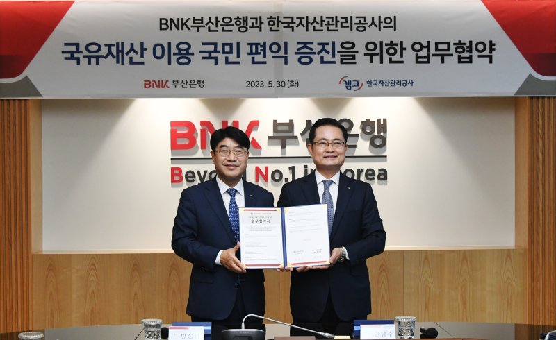 BNK부산은행 방성빈 은행장(왼쪽)과 한국자산관리공사 권남주 사장이 업무협약서를 들고 기념촬영을 하고 있다. BNK부산은행 제공