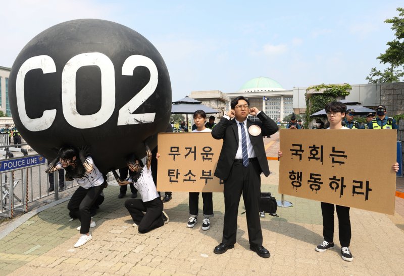 그린피스 회원들이 세계 환경의 날인 5일 서울 여의도 국회 앞에서 기후위기 대응을 촉구하는 '탄소(CO2)의 짐' 퍼포먼스를 하고 있다. 2023.6.5/뉴스1 ⓒ News1 신웅수 기자