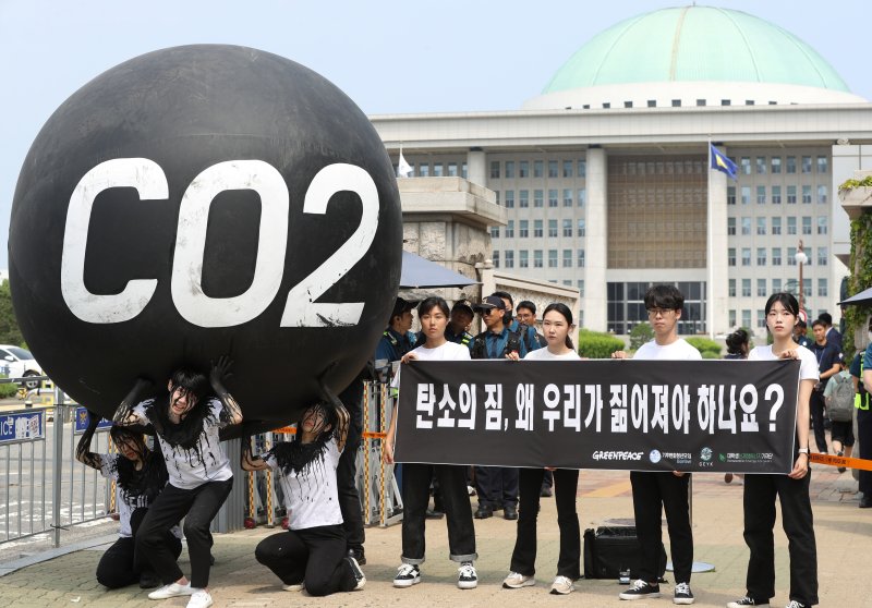 그린피스 회원들이 세계 환경의 날인 5일 서울 여의도 국회 앞에서 기후위기 대응을 촉구하는 '탄소(CO2)의 짐' 퍼포먼스를 하고 있다. 2023.6.5/뉴스1 ⓒ News1 신웅수 기자