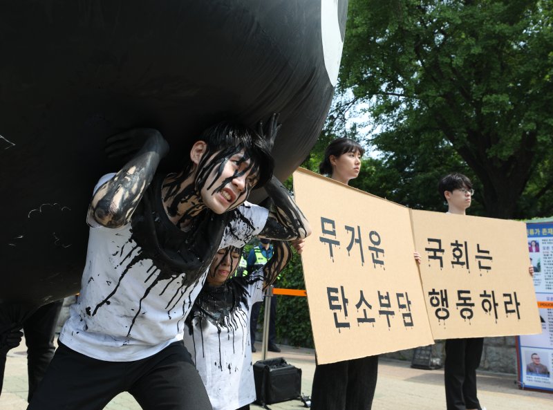 그린피스 회원들이 세계 환경의 날인 5일 서울 여의도 국회 앞에서 기후위기 대응을 촉구하는 '탄소(CO2)의 짐' 퍼포먼스를 하고 있다. 2023.6.5/뉴스1 ⓒ News1 신웅수 기자