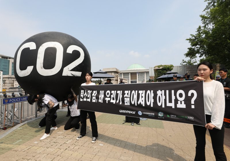 그린피스 회원들이 세계 환경의 날인 5일 서울 여의도 국회 앞에서 기후위기 대응을 촉구하는 '탄소(CO2)의 짐' 퍼포먼스를 하고 있다. 2023.6.5/뉴스1 ⓒ News1 신웅수 기자