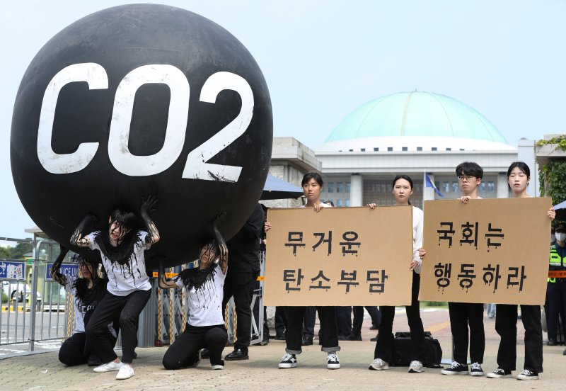 그린피스 회원들이 세계 환경의 날인 5일 서울 여의도 국회 앞에서 기후위기 대응을 촉구하는 '탄소(CO2)의 짐' 퍼포먼스를 하고 있다. 2023.6.5/뉴스1 ⓒ News1 신웅수 기자