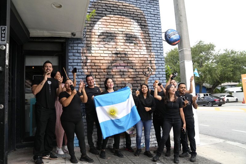 7일(현지시간) 미국 플로리다주 마이애미의 아르헨티나 음식점 직원들이 리오넬 메시의 벽화 앞에서 아르헨티나 국기를 들고 즐거워하고 있다. 메시는 북미축구리그 MLS의 인터 마이애미에서 뛸 것이라고 밝혔다.AP뉴시스