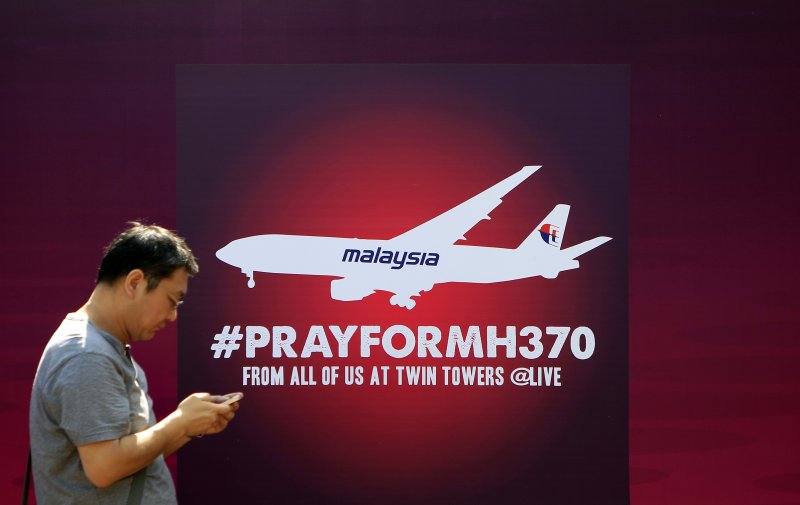 지난 2014년 3월15일(현지시간) 말레이시아 쿠알라룸푸르에서 한 시민이 "MH370을 위해 기도하자"라는 안내문 앞을 지나고 있다. MH370편은 당시 쿠알라룸푸르를 이륙한 후 실종됐으며 수색 작업에도 기체는 발견되지 않고 있다. 싱가포르 출신 코미디언은 실종 사건을 조롱해 말레이시아의 분노를 사고 있다.AP뉴시스
