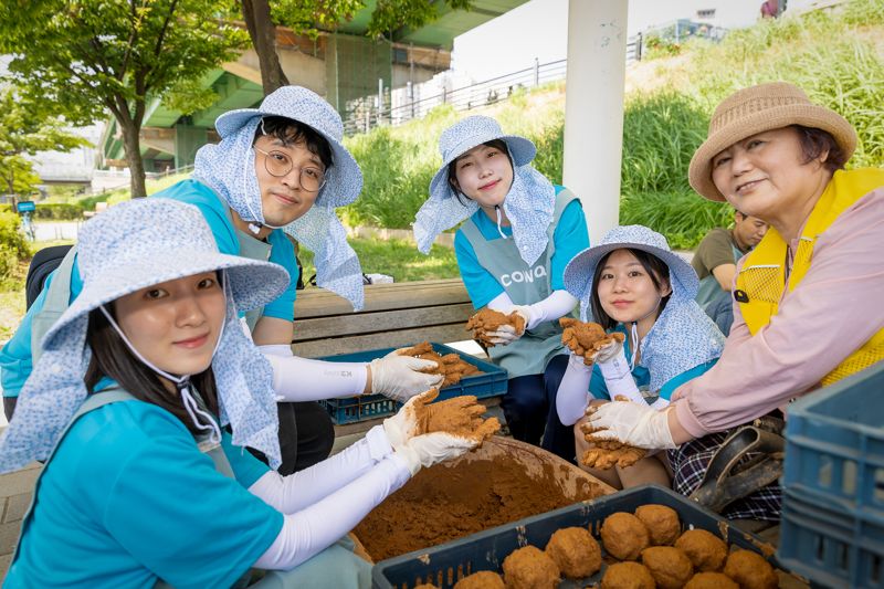 코웨이 직원들이 안양천 수질을 정화하기 위한 EM흙공을 만들고 있다. 코웨이 제공.