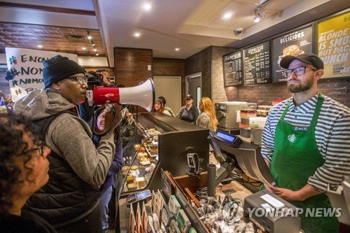 FILE - In this April 15, 2018, file photo, Asa Khalif, left, a Black Lives Matter activist from Philadelphia, demands the firing of a Starbucks cafe manager who called police, resulting in the arrest of two black men Thursday, April 12, 2018, at the Starbucks cafe in Philadelphia. The two men, Rasho