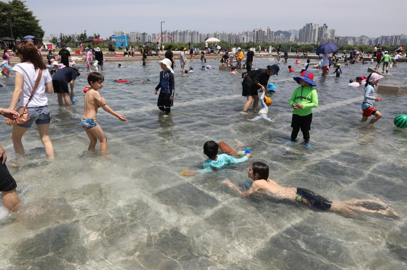 서울 전역에 폭염주의보가 발효된 18일 서울 영등포구 여의도 한강시민공원 물빛광장에서 시민들이 물놀이를 하며 더위를 식히고 있다. 2023.6.18/뉴스1 ⓒ News1 송원영 기자