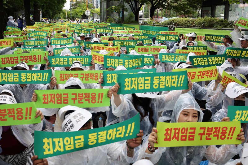 지난해 6월 서울 국회의사당역 인근에서 열린 최저임금 동결 촉구 결의대회에서 소상공인연합회원들이 관련 손피켓을 들어보이고 있다. 연합뉴스