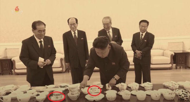 아동용 그릇을 보고 있는 김정은 노동당 총비서의 모습. 일본 캐릭터 도라에몽(왼쪽 원)과 일본 캐릭터 헬로키티(오른쪽 원)가 보인다.(조선중앙TV 조선기록영화 인민의 어버이 갈무리)