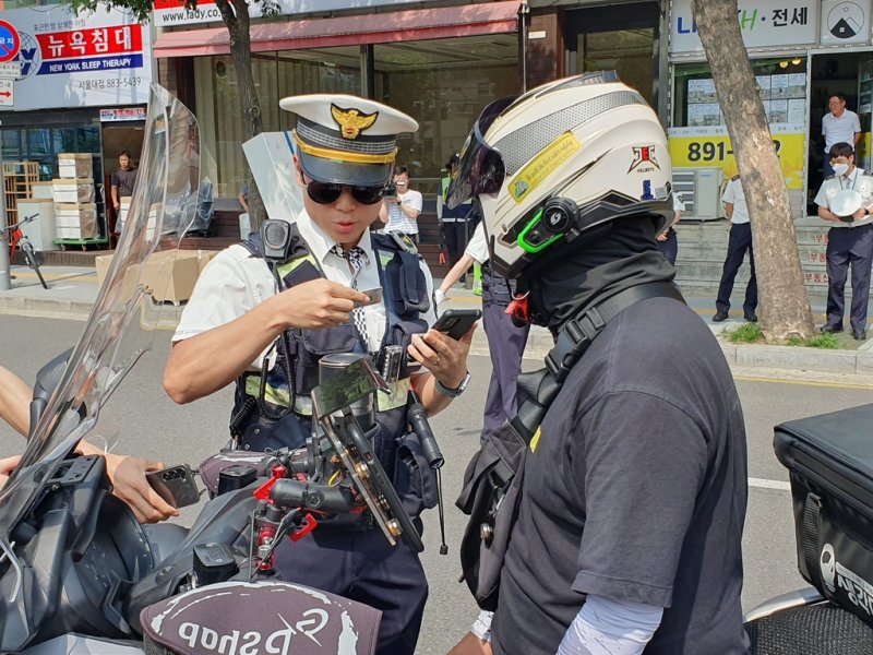 오토바이 운전자의 면허증을 확인하는 경찰 [촬영 최원정]