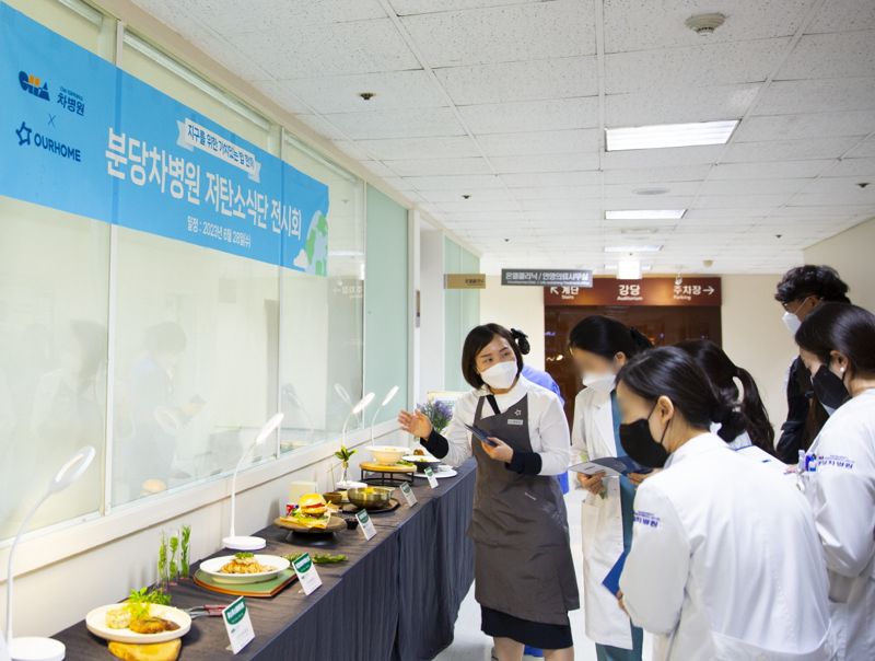 아워홈 소속 영양사가 지난 28일 경기 성남시 분당차병원 직원식당에서 열린 ‘저탄소 식단 전시회’에 전시된 6단계 비건 식단을 소개하고 있다. 아워홈 제공