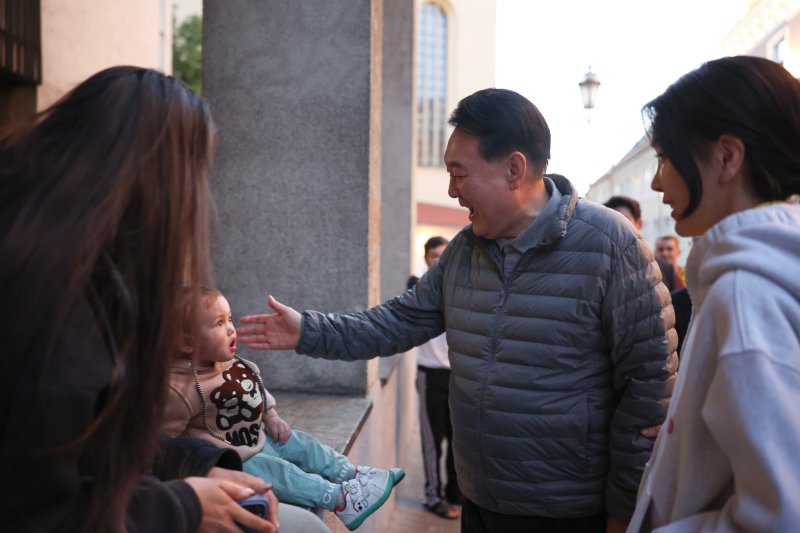 북대서양조약기구(NATO·나토) 정상회의 참석차 리투아니아를 방문 중인 윤석열 대통령과 김건희 여사가 10일(현지시간) 빌뉴스 구시가지를 산책하던 중 아이와 인사를 나누고 있다. 빌뉴스 구시가지는 유네스코에 의해 세계문화유산으로 등재된 곳이다. 2023.7.11 [공동취재] kane@yna.co.kr (끝)