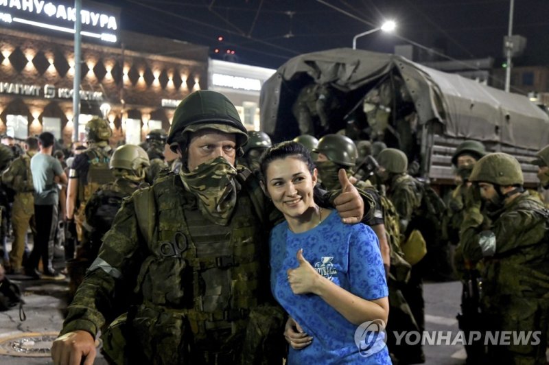 철수하는 러 바그너 그룹 용병과 기념촬영하는 주민 (출처=연합뉴스)