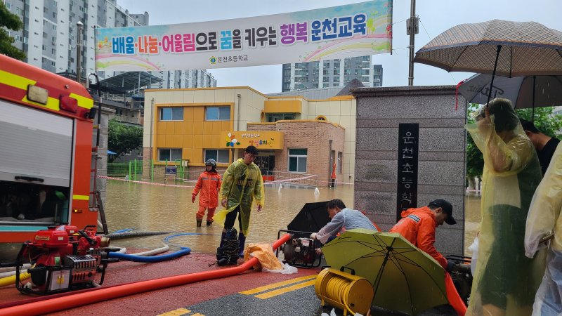 15일 오전 사흘째 이어진 장맛비에 충북 청주시 흥덕구 운천동 운천초등학교가 침수돼 소방당국과 주민들이 배수 작업을 벌이고 있다.2023.7.15/ⓒ 뉴스1 박재원 기자
