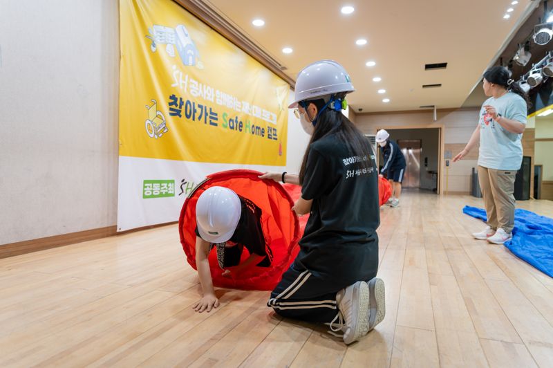 지난 17일 SH공사와 더프라미스는 서울 양천구 봉영여자중학교 2학년 학생 141명을 대상으로 시민과 함께하는 재난 대비 훈련 프로그램 ‘찾아가는 SH(Safe Home) 캠프’를 개최했다.재난 상황에서의 좁은 장소에서 대피 체험이 진행되고 있다. SH공사 제공