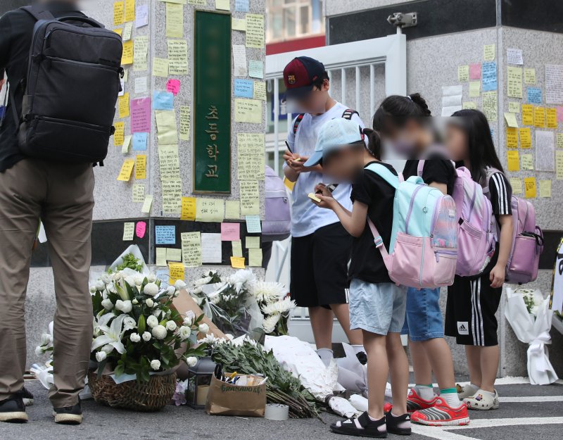 20일 오전 서울 서초구의 한 초등학교 정문에서 학생들이 추모 메시지를 적고 있다. 뉴스1