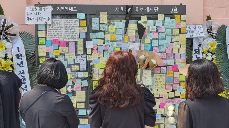 검은 옷을 입은 추모객들이 서이초등학교 사거리 벽에 붙은 메모를 읽고 있다. 사진=김성환기자