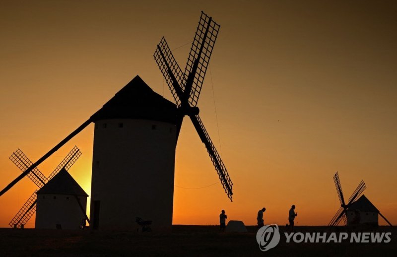 라만차의 풍차 TOPSHOT - Ancient windmills are seen in the upper part of the village of Campo de Criptana, Castilla La Mancha region, central Spain, on July 3, 2023. The windmills are famous since the 17th century, when Don Quixote, the famous novel of Cervantes, was first published and introduced the scen