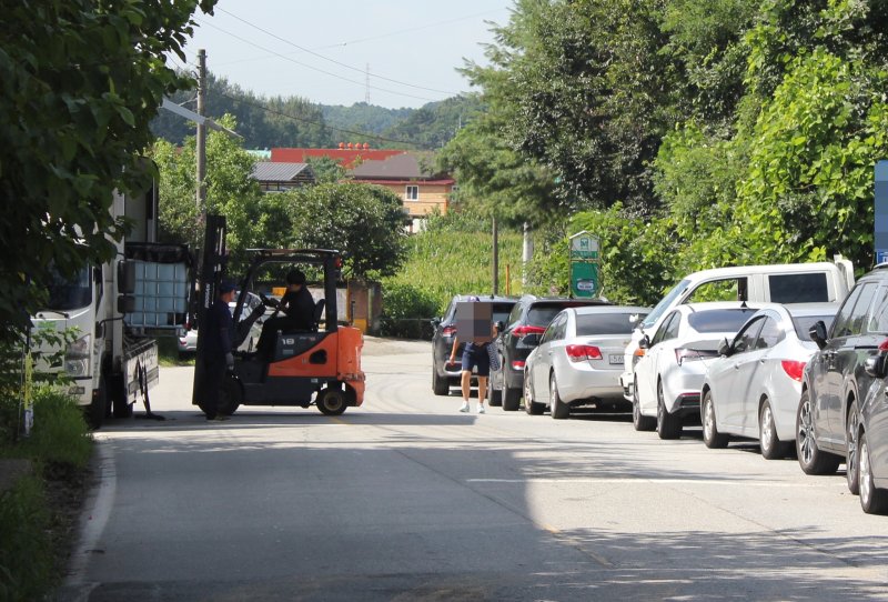 충북 청주시 서원구 현도면 중삼리 한 도로. 진출입로로 사용하던 사유지가 막히자 업체 관계자들이 도로 위에 대형 화물차를 세운 뒤 물건을 실어 나르고 있다. 2023.7.26/뉴스1