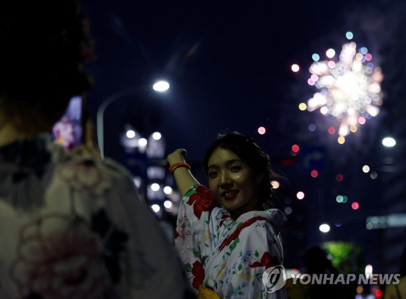 불꽃놀이 배경으로 기념사진 찍는 여성 A Chinese tourist wearing yukata, Summer Kimono, takes photos at Sumidagawa fireworks festival in Tokyo, Japan, July 29, 2023. The fireworks festival returned for the first time in four years following the lift of COVID-19 restrictions. REUTERS/Kim Kyung-Hoon