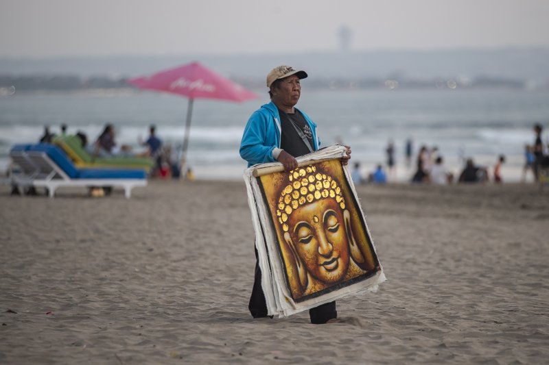 지난 8월 1일 인도네시아 발리섬 세미냑의 해변에서 현지 행상인이 그림을 팔기 위해 관광객을 찾고 있다.EPA연합뉴스