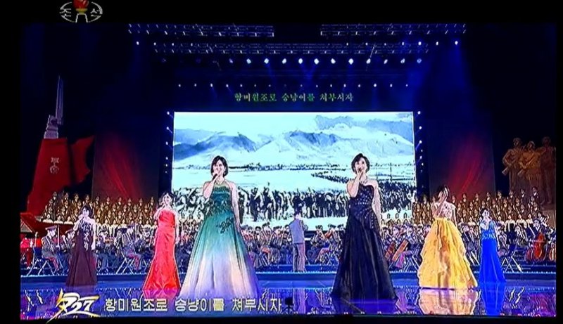 북한 모란봉악단 소속 일부 가수들이 전승절 70주년 기념 경축 공연에서 노래를 부르고 있다. 왼쪽에서 첫 번째 박미경, 왼쪽에서 세 번째 조국향, 왼쪽에서 네 번째 정수향, 왼쪽에서 다섯 번째 김유경.(조선중앙TV 갈무리)