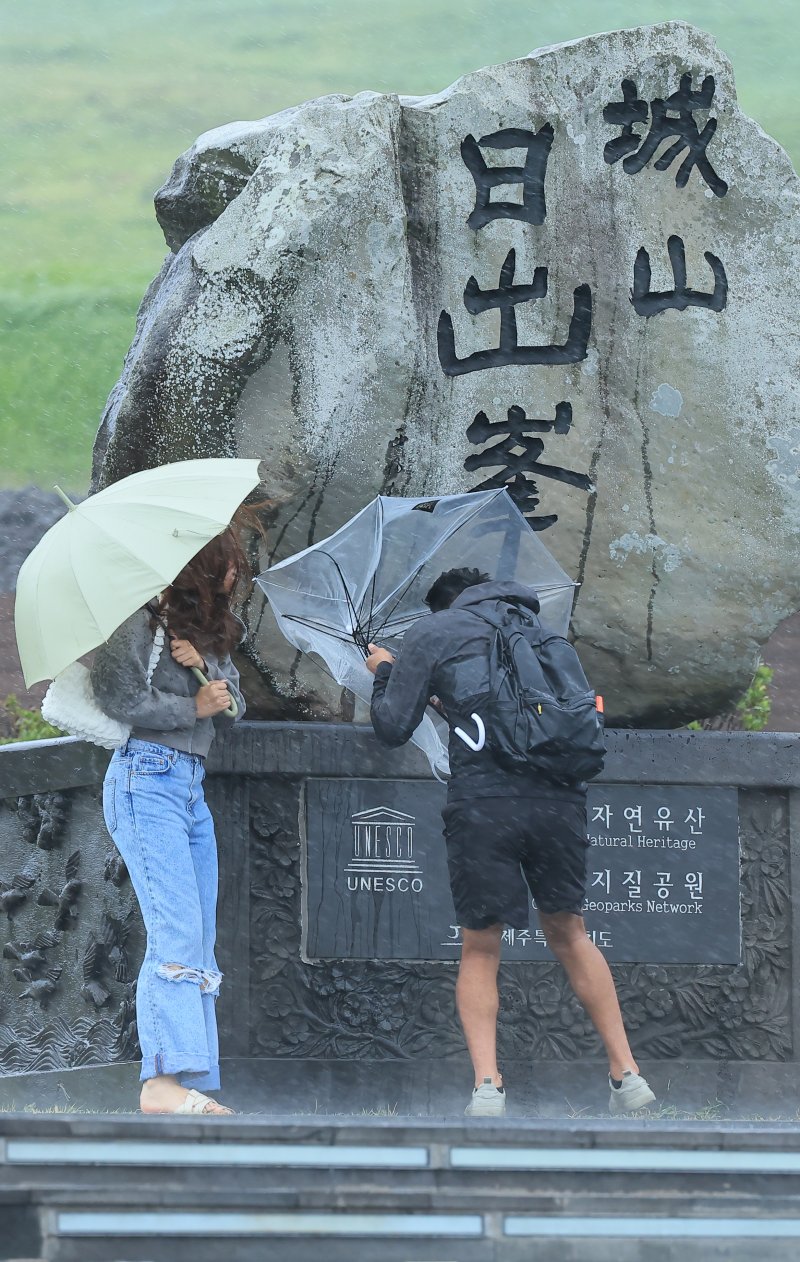 제6호 태풍 '카눈'의 영향으로 9일 제주 서귀포시 성산일출봉을 찾은 관광객들이 강한 비바람을 맞고 있다. 카눈은 기상청 관측 이래 사상 처음으로 한반도를 남북 종단할 것으로 예측됐다. 연합뉴스