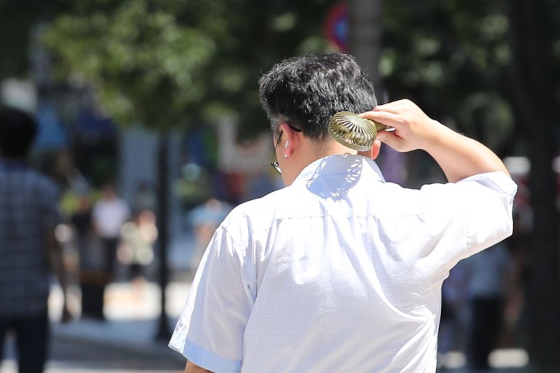 서울지역에 폭염 경보가 발령된 지난 8일 서울 종로구 광화문광장에서 한 시민이 선풍기를 목에 쐬고 있다. 뉴시스