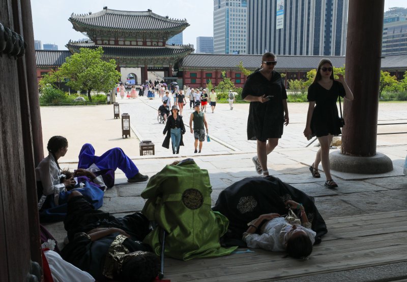 폭염이 기승을 부렸던 지난 8월 15일 서울 종로구 경복궁을 찾은 외국인 관광객들이 더위에 지쳐 누워있다.뉴스1 제공.