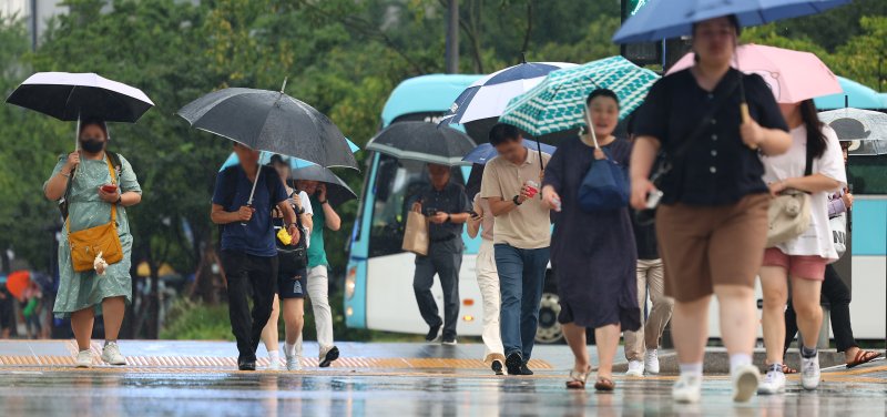 절기상 더위가 가신다는 처서를 하루 앞둔 22일 오후 소나기가 내린 서울 세종로사거리에서 우산을 쓴 시민들이 길을 지나고 있다. 23일은 전국적으로 흐리고 비가 내리겠으며 서울과 경기 남부 지역에는 30∼100mm의 비가 내릴 것으로 예상된다. 연합뉴스