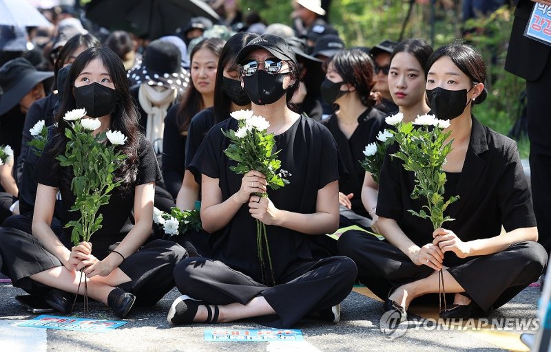 교사들이 지난 2일 오후 서울 영등포구 국회대로에서 열린 '50만 교원 총궐기 추모 집회'에 국화를 들고 참석하고 있다. 연합뉴스