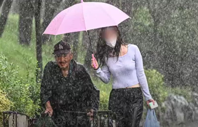 폐지 줍는 노인에게 우산을 씌워주며 함께 걸은 여성. 연합뉴스TV 보도화면 갈무리