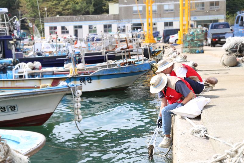 송정항 일대 연안정화에 한창인 롯데월드 어드벤처 부산 샤롯데 봉사단 모습. 롯데월드 어드벤처 부산 제공