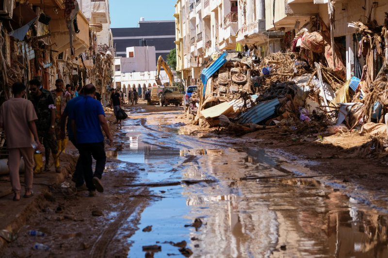 리비아 동부 데르나에서 13일(현지시간) 시민들이 댐 붕괴로 부서진 시가지를 지나고 있다.로이터뉴스1