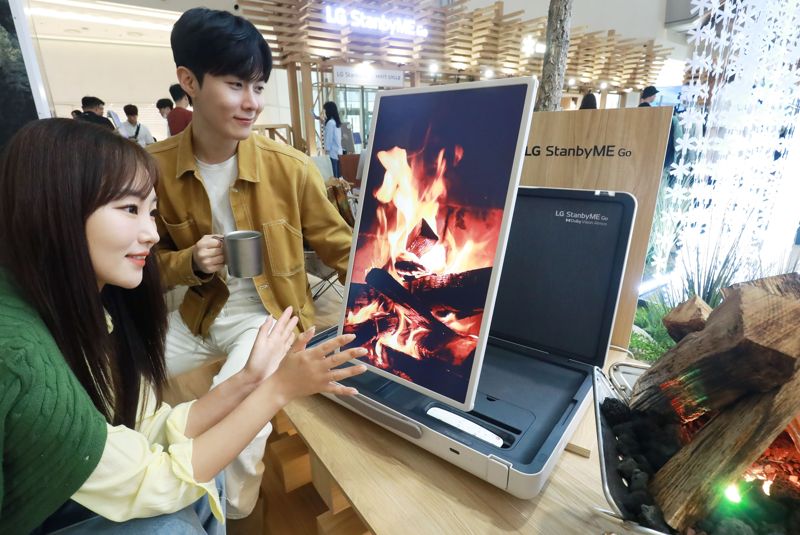LG전자 모델들이 오는 24일까지 서울 롯데월드몰 내 통나무 산장 콘셉트 캠핑 공간으로 운영되는 'LG 스탠바이미 Go' 팝업스토어에서 제품을 체험하고 있다. LG전자 제공