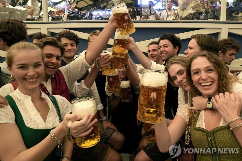 Festival goer with glasses of beer pose for a photo on day one of the 188th 'Oktoberfest' beer festival in Munich, Germany, Saturday, Sept. 16, 2023. (AP Photo/Matthias Schrader)