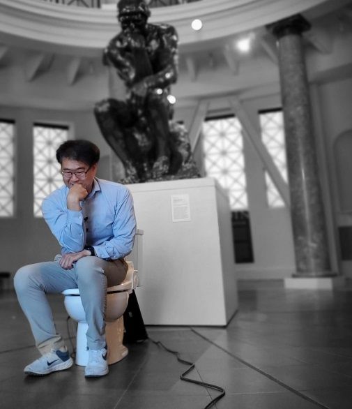 박승민 미국 스탠퍼드대 비뇨기의학과 연구원이 대학 구내의 로뎅의 ‘생각하는 사람’ 조각상 앞에 변기를 두고 그 위에 앉아있다. 출처=미국 스탠퍼드대