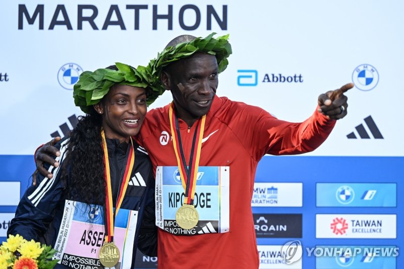 2023 베를린 마라톤 챔피언 epaselect epa10880256 Women?s winner Tigst Assefa of Ethiopia (L) and Men?s winner Eliud Kipchoge of Kenya (R) celebrate during the flower ceremony of the Berlin Marathon 2023, in Berlin, Germany, 24 September 2023. Assefa set a new women's world record of 2:11:53. EPA/Filip Singer